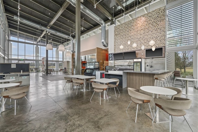 dining area with concrete flooring and a towering ceiling