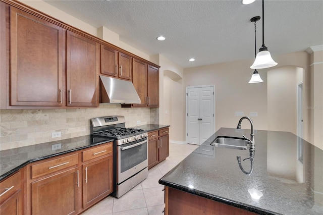 kitchen featuring sink, gas stove, a center island with sink, light tile patterned floors, and pendant lighting