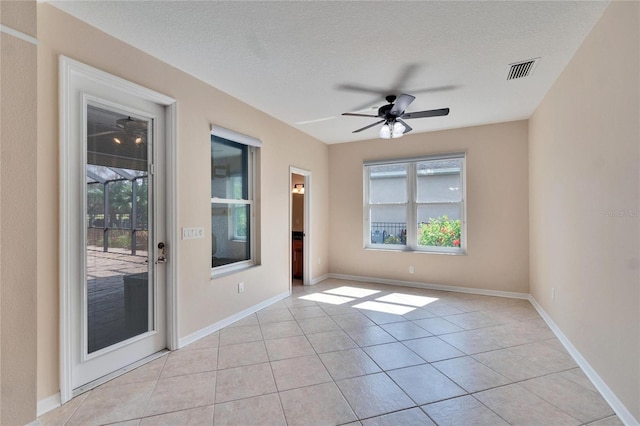 empty room with plenty of natural light, a textured ceiling, and light tile patterned flooring