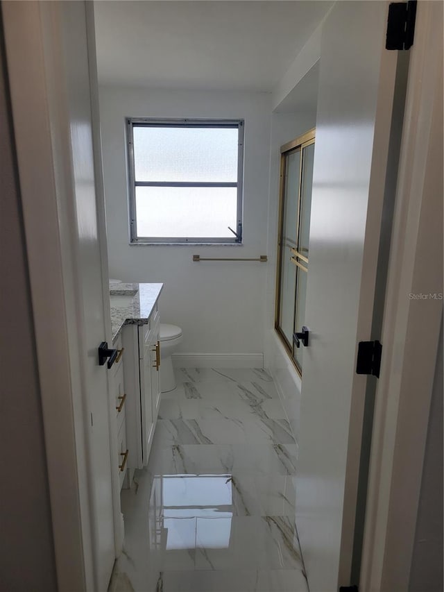 full bathroom with enclosed tub / shower combo, toilet, and vanity