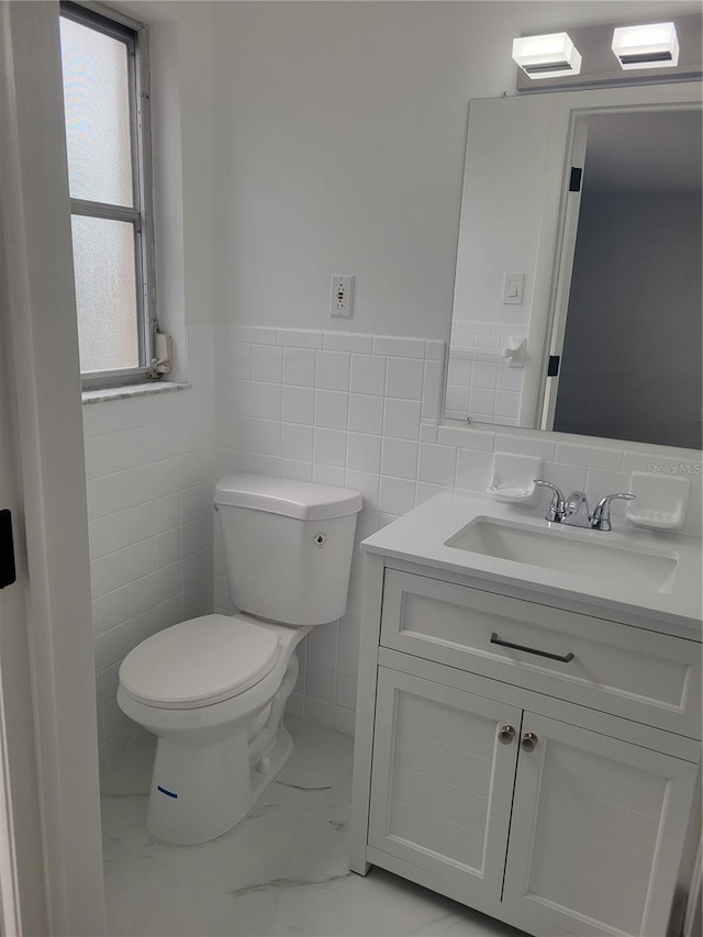 bathroom with toilet, vanity, and tile walls