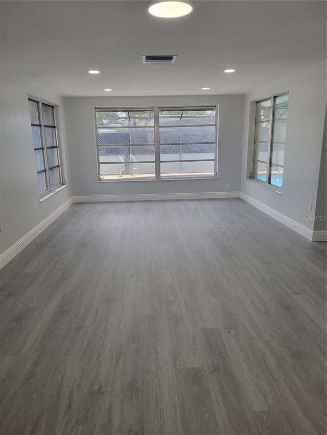 empty room with a wealth of natural light and dark hardwood / wood-style flooring