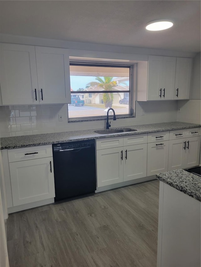 kitchen featuring stone counters, sink, black dishwasher, light hardwood / wood-style flooring, and white cabinetry