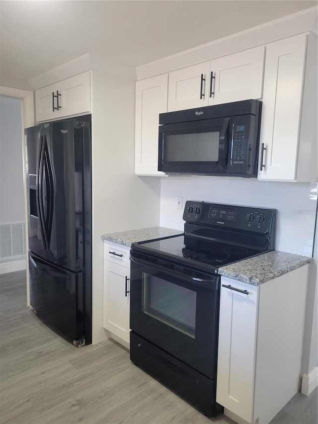 kitchen featuring black appliances, white cabinets, light stone countertops, and light hardwood / wood-style floors