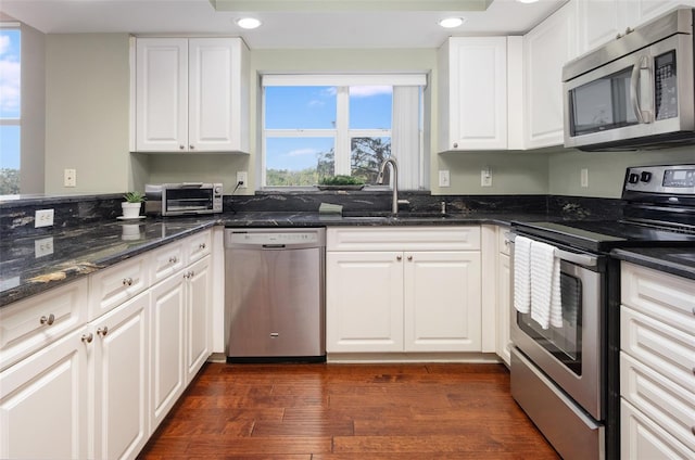 kitchen featuring dark stone countertops, sink, stainless steel appliances, and white cabinets