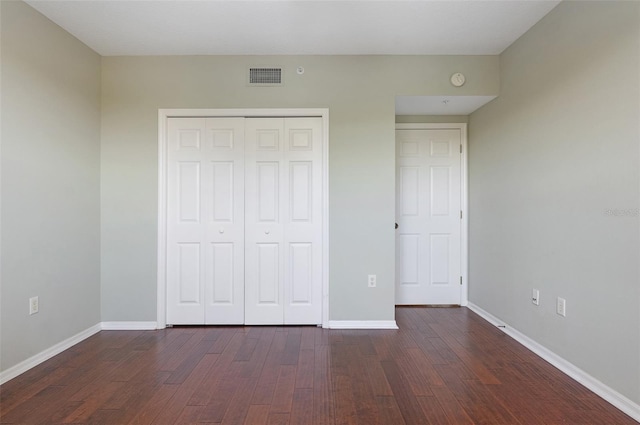 unfurnished bedroom with a closet and dark hardwood / wood-style floors