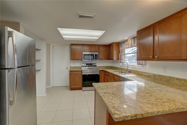 kitchen featuring light tile patterned flooring, sink, light stone counters, kitchen peninsula, and stainless steel appliances