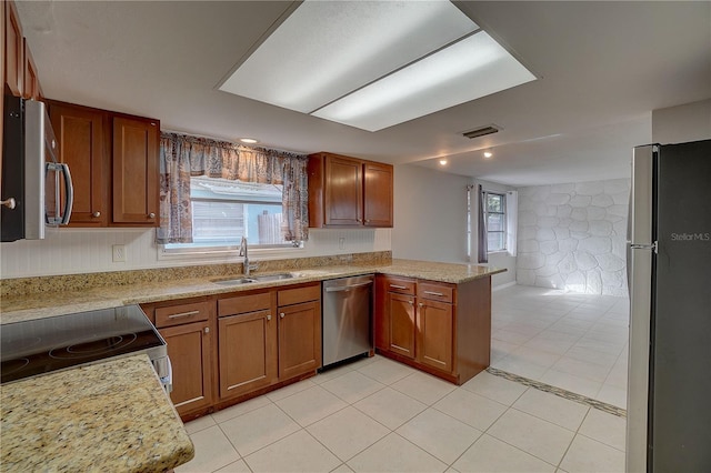 kitchen featuring sink, light stone counters, light tile patterned floors, kitchen peninsula, and stainless steel appliances