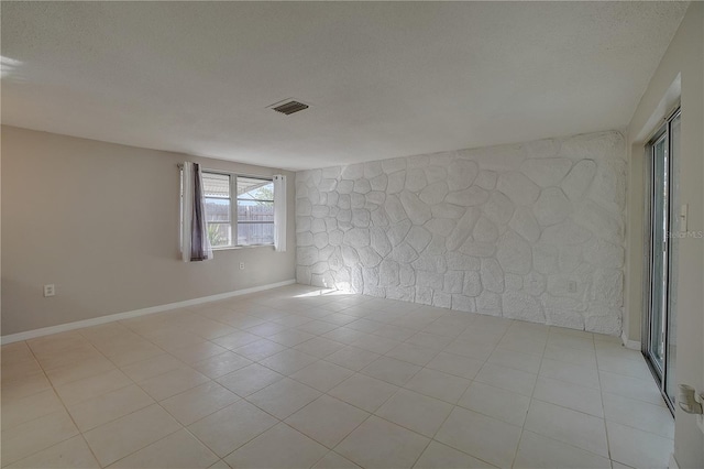 spare room featuring light tile patterned flooring and a textured ceiling