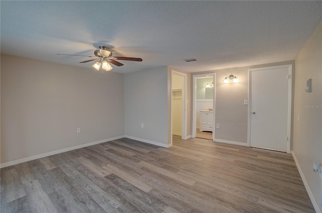 unfurnished room with ceiling fan, a textured ceiling, and light wood-type flooring