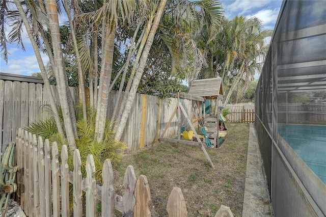 view of yard with a lanai, a fenced in pool, and a playground