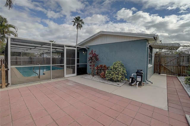 rear view of house featuring a fenced in pool, a patio area, and glass enclosure