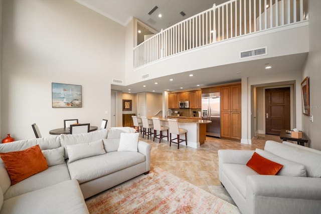 living room featuring light tile patterned floors, a towering ceiling, and sink