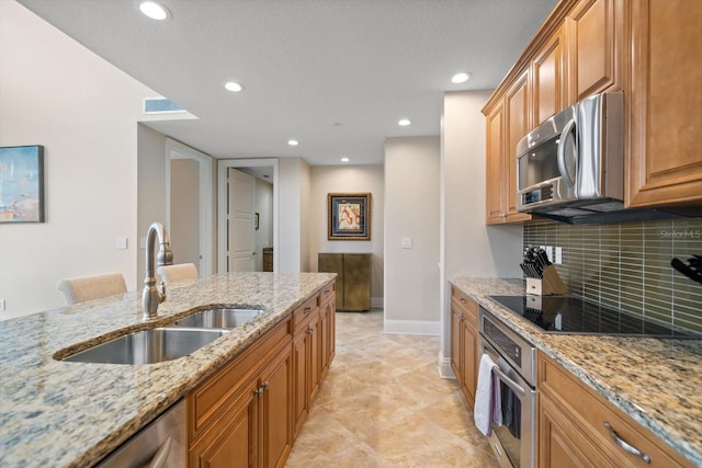 kitchen featuring light stone countertops, appliances with stainless steel finishes, decorative backsplash, and sink