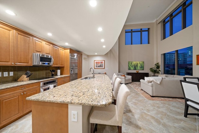 kitchen featuring stainless steel appliances, sink, a kitchen bar, and a kitchen island with sink