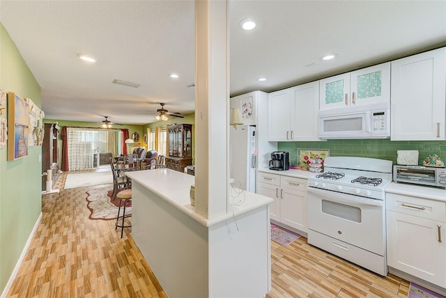 kitchen with white appliances, white cabinets, light wood-type flooring, a breakfast bar, and backsplash