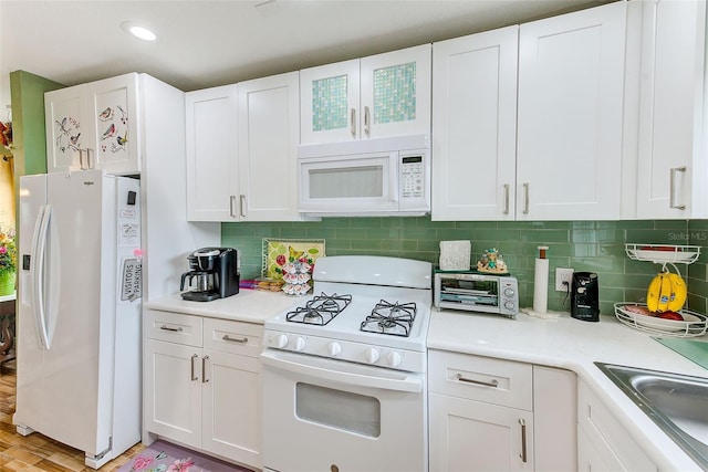 kitchen with sink, light wood-type flooring, tasteful backsplash, white cabinets, and white appliances