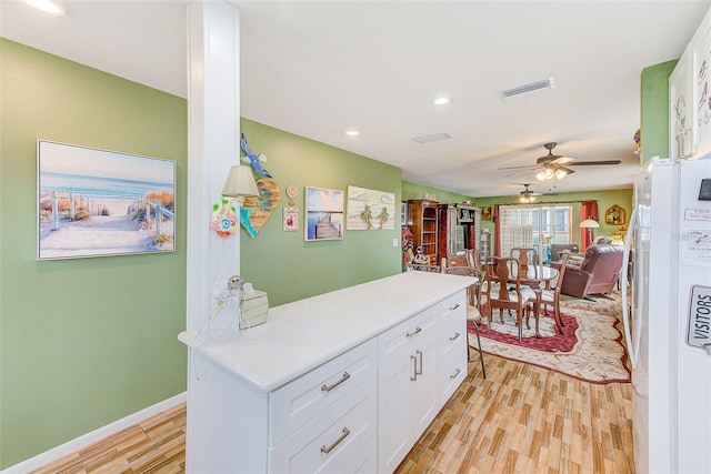 kitchen with white cabinets, ceiling fan, light hardwood / wood-style floors, and white fridge