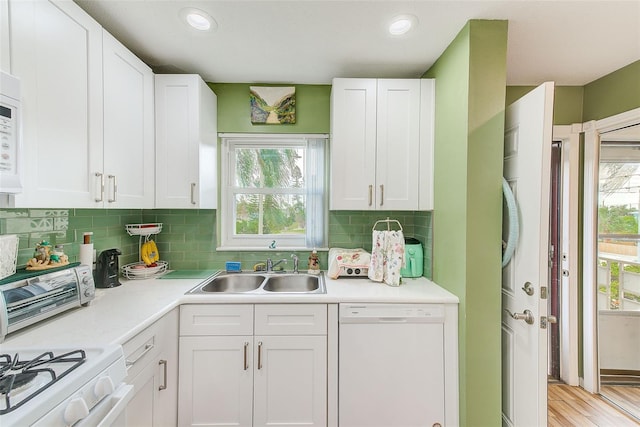 kitchen with light hardwood / wood-style flooring, sink, white cabinetry, white appliances, and decorative backsplash