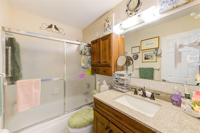 full bathroom featuring vanity, backsplash, combined bath / shower with glass door, and toilet