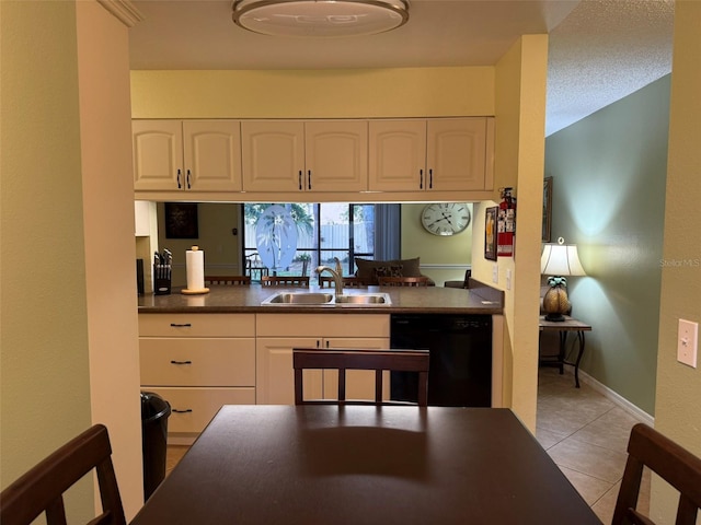 kitchen featuring dishwasher, sink, white cabinetry, light tile patterned flooring, and a textured ceiling