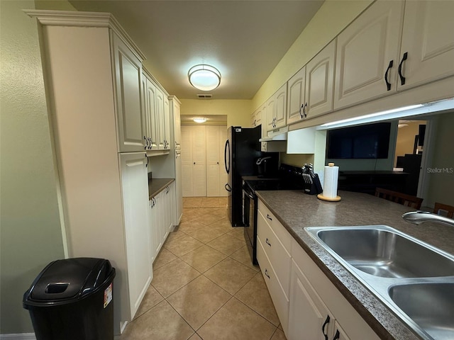 kitchen featuring sink, light tile patterned floors, and black electric range