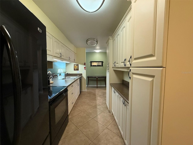 kitchen with sink, black appliances, white cabinets, and light tile patterned floors