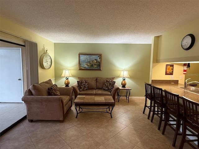 living room with sink, a textured ceiling, and tile patterned floors