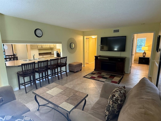 tiled living room with sink and a textured ceiling