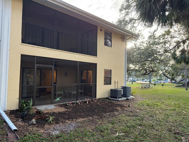 back of property featuring central air condition unit, a sunroom, and a yard