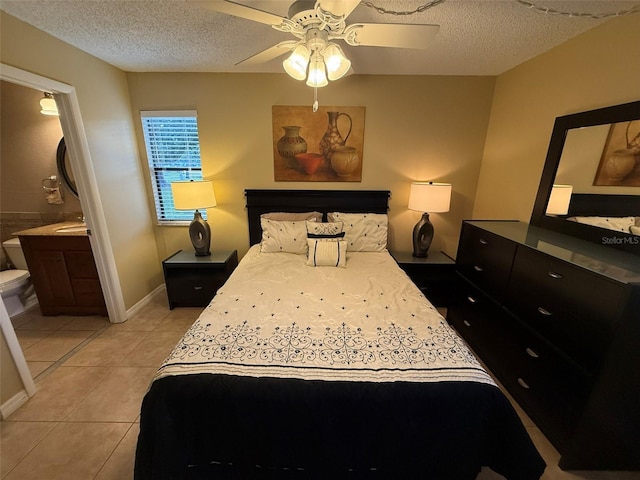 bedroom with ceiling fan, connected bathroom, a textured ceiling, and light tile patterned flooring