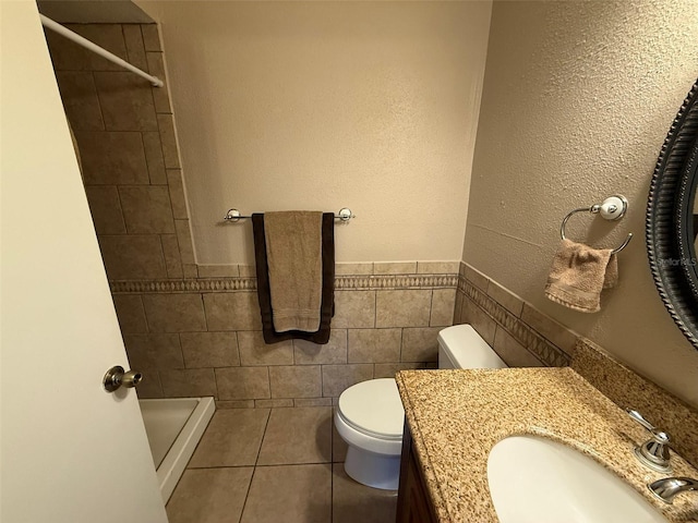 bathroom featuring tile patterned flooring, vanity, tile walls, toilet, and tiled shower