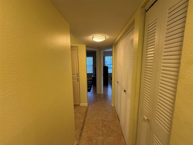 hall featuring a textured ceiling and light tile patterned floors