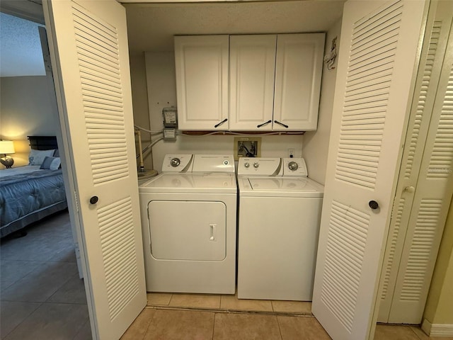 laundry area featuring light tile patterned flooring, cabinets, and independent washer and dryer