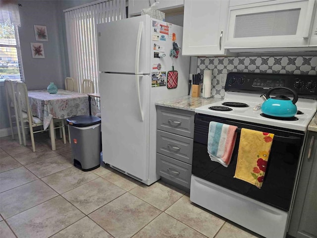 kitchen featuring tasteful backsplash, white cabinets, light tile patterned floors, and white appliances