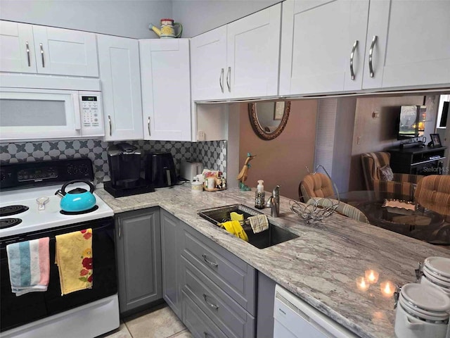 kitchen with white cabinetry, backsplash, white appliances, light stone counters, and sink