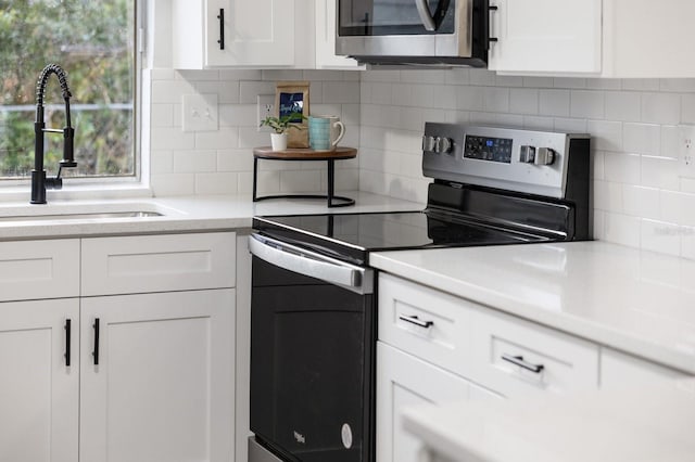 kitchen with tasteful backsplash, appliances with stainless steel finishes, sink, and white cabinetry