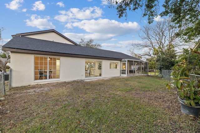 back of property with a sunroom and a lawn