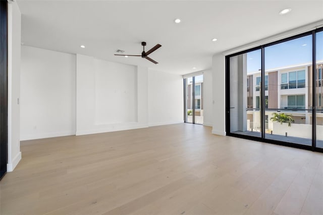 unfurnished room with ceiling fan, a wall of windows, and light hardwood / wood-style flooring