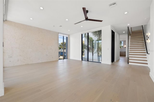 unfurnished living room featuring light wood-type flooring, ceiling fan, and floor to ceiling windows