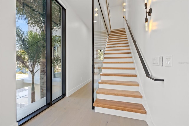 stairs featuring expansive windows and hardwood / wood-style floors