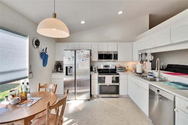 kitchen with appliances with stainless steel finishes, white cabinetry, sink, hanging light fixtures, and high vaulted ceiling