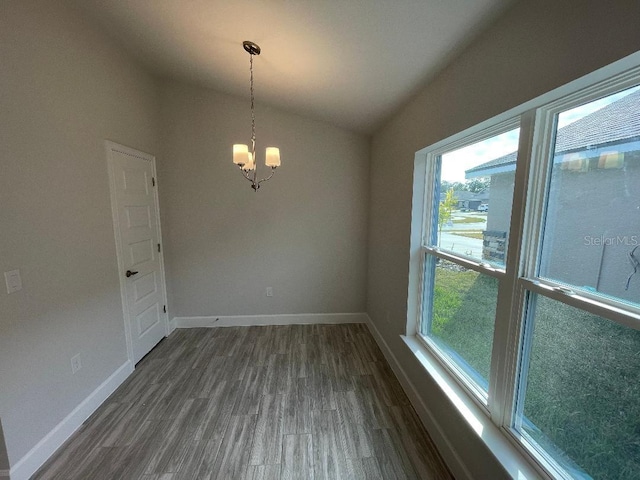 empty room with vaulted ceiling, dark wood-type flooring, and a chandelier