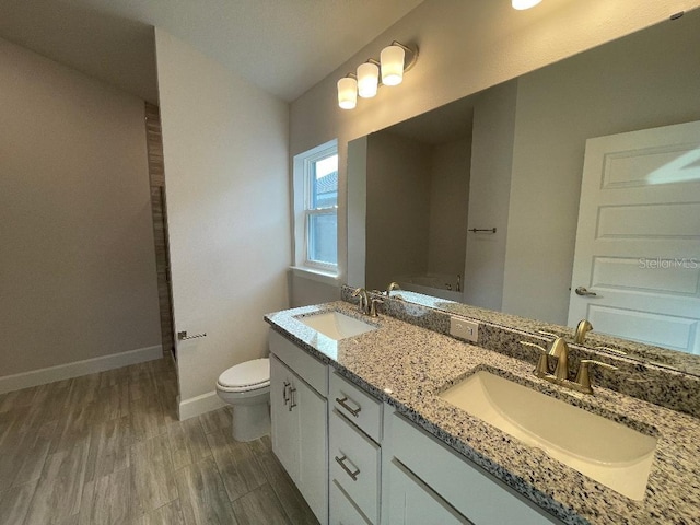 bathroom featuring toilet, a tub, hardwood / wood-style flooring, and vanity