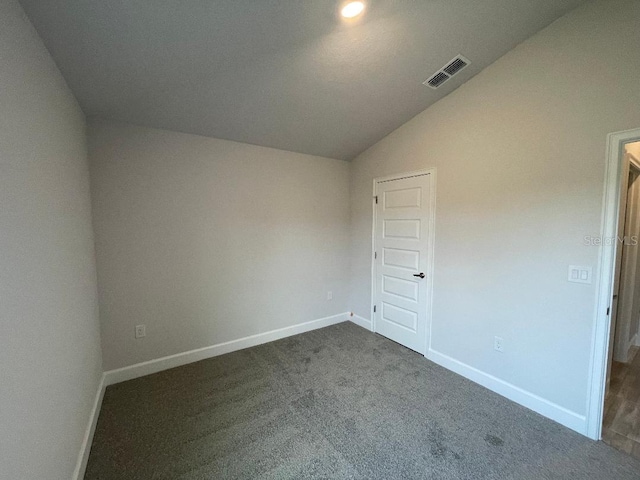 unfurnished bedroom featuring lofted ceiling and dark carpet