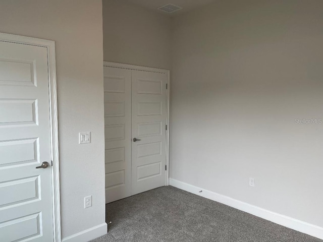 unfurnished bedroom with a closet and dark carpet