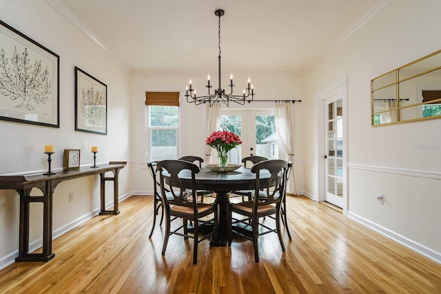 dining space featuring an inviting chandelier, crown molding, light hardwood / wood-style flooring, and french doors