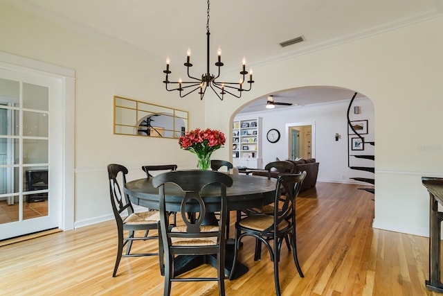 dining room with crown molding, light hardwood / wood-style flooring, built in features, and ceiling fan with notable chandelier