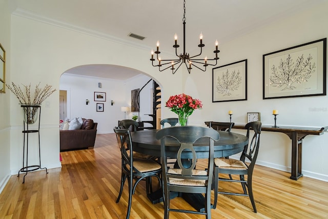 dining area featuring crown molding, light hardwood / wood-style flooring, and a notable chandelier