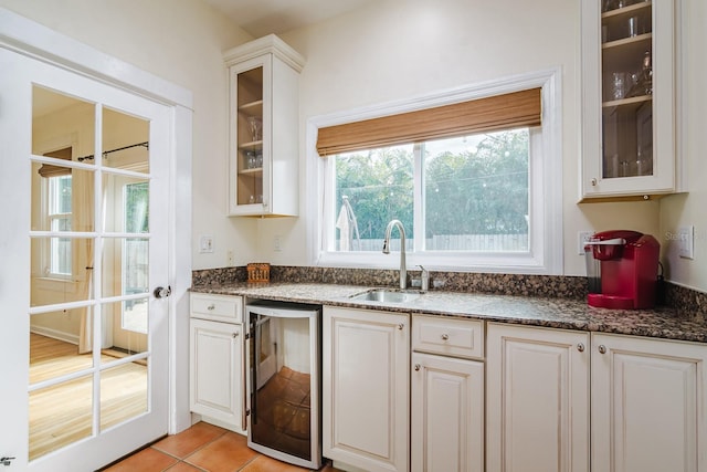 kitchen featuring sink, light tile patterned floors, beverage cooler, and white cabinets